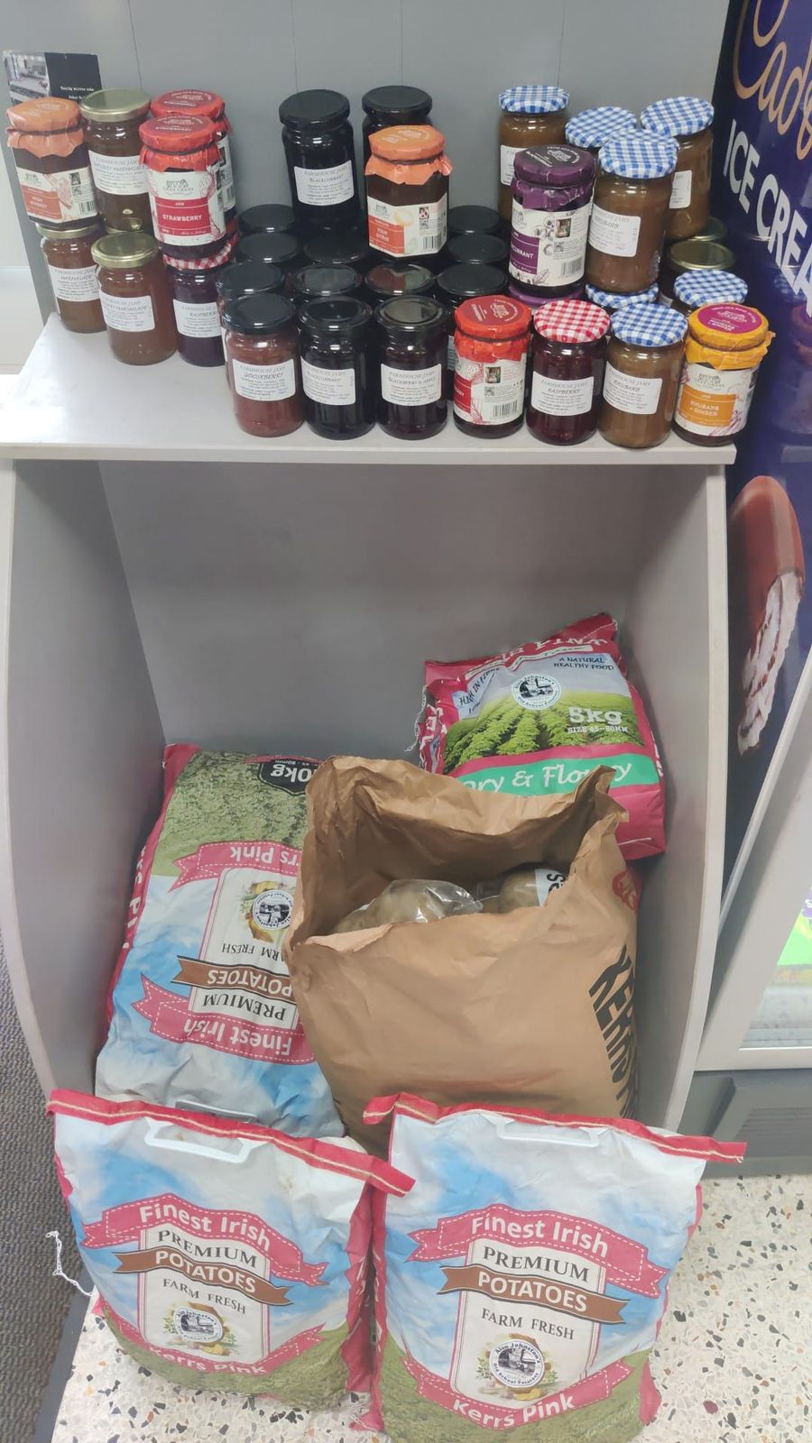 Jars of jam and chutney above sacks of Kerr's Pink and Irish potatoes